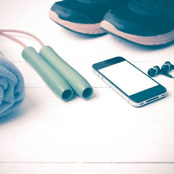 fitness equipment : running shoes,towel,jumping rope and phone on white wood table vintage style
