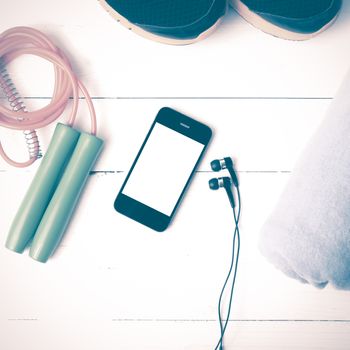 fitness equipment : running shoes,towel,jumping rope and phone on white wood table vintage style