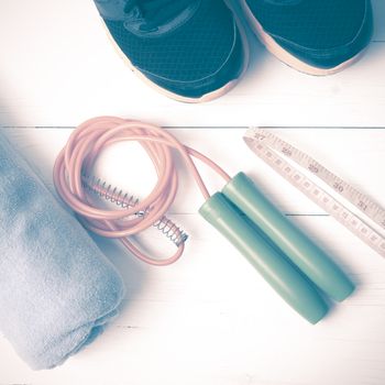 fitness equipment : running shoes,towel,jumping rope and measuring tape on white wood table vintage style