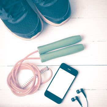 fitness equipment : running shoes,jumping rope and phone on white wood table vintage style