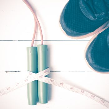 fitness equipment : running shoes,jumping rope and measuring tape on white wood table vintage style