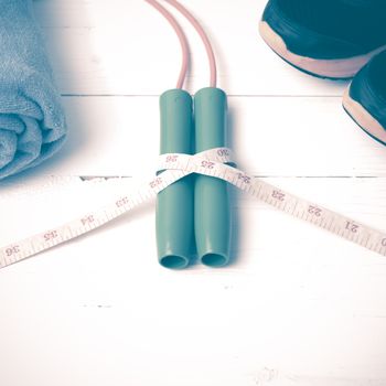 fitness equipment : running shoes,towel,jumping rope and measuring tape on white wood table vintage style