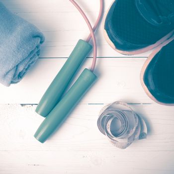 fitness equipment : running shoes,towel,jumping rope and measuring tape on white wood table vintage style