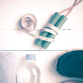 fitness equipment : running shoes,towel,jumping rope,water bottle and measuring tape on white wood table vintage style