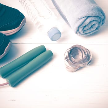 fitness equipment : running shoes,towel,jumping rope,water bottle and measuring tape on white wood table vintage style