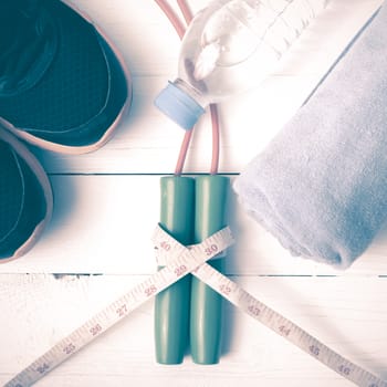 fitness equipment : running shoes,towel,jumping rope,water bottle and measuring tape on white wood table vintage style