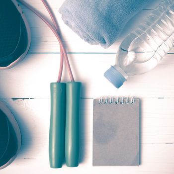 fitness equipment : running shoes,towel,jumping rope,water bottle and notepad on white wood table vintage style