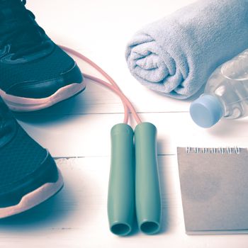 fitness equipment : running shoes,towel,jumping rope,water bottle and notepad on white wood table vintage style