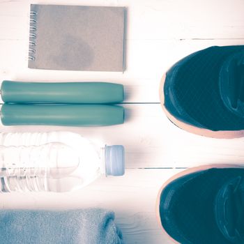 fitness equipment : running shoes,towel,jumping rope,water bottle and notepad on white wood table vintage style