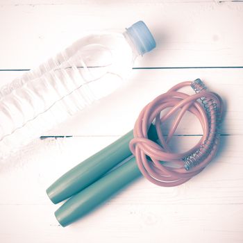 fitness equipment :jumping rope and water bottle on white wood table vintage style