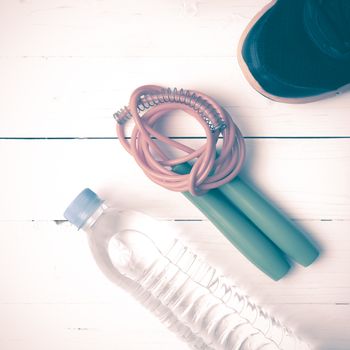 fitness equipment : running shoes,jumping rope and water bottle on white wood table vintage style