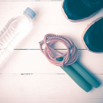 fitness equipment : running shoes,jumping rope and water bottle on white wood table vintage style