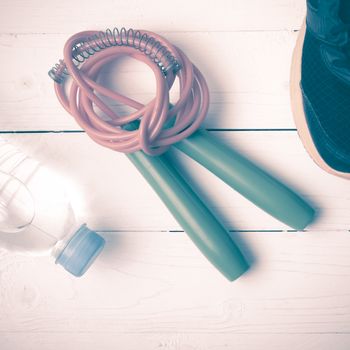 fitness equipment : running shoes,jumping rope and water bottle on white wood table vintage style