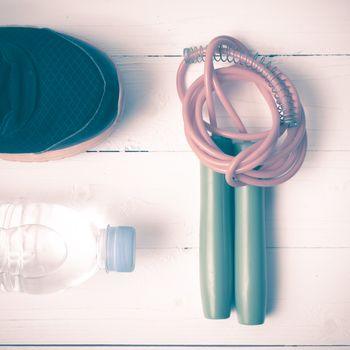 fitness equipment : running shoes,jumping rope and water bottle on white wood table vintage style