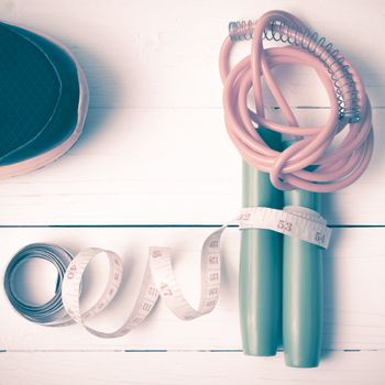 fitness equipment : running shoes,jumping rope and measuring tape on white wood table vintage style