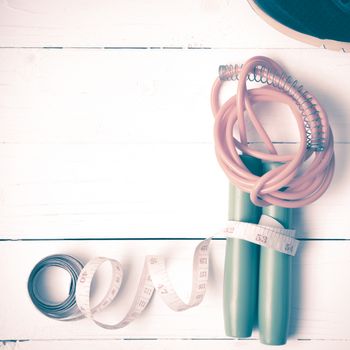 fitness equipment : running shoes,jumping rope and measuring tape on white wood table vintage style