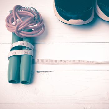 fitness equipment : running shoes,jumping rope and measuring tape on white wood table vintage style