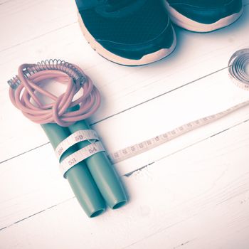 fitness equipment : running shoes,jumping rope and measuring tape on white wood table vintage style