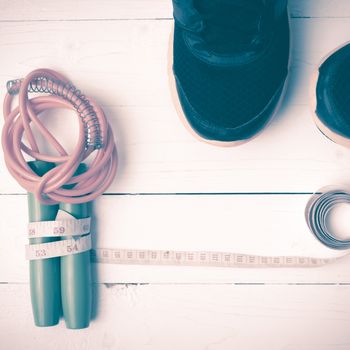 fitness equipment : running shoes,jumping rope and measuring tape on white wood table vintage style