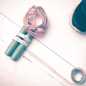 fitness equipment : running shoes,jumping rope and measuring tape on white wood table vintage style