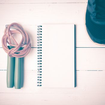 fitness equipment : running shoes,jumping rope and notepad on white wood table vintage style