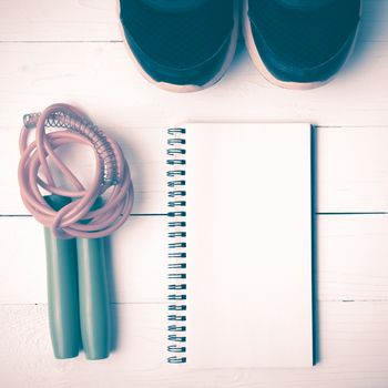 fitness equipment : running shoes,jumping rope and notepad on white wood table vintage style