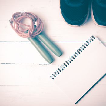 fitness equipment : running shoes,jumping rope and notepad on white wood table vintage style