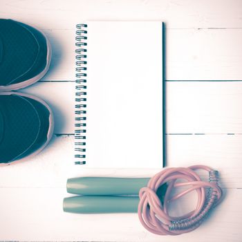 fitness equipment : running shoes,jumping rope and notepad on white wood table vintage style