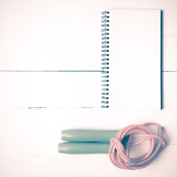 fitness equipment : jumping rope and notepad on white wood table vintage style