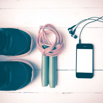 fitness equipment : running shoes,jumping rope and phone on white wood table vintage style