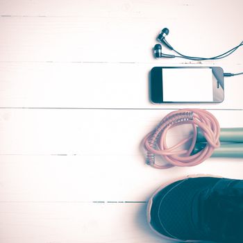 fitness equipment : running shoes,jumping rope and phone on white wood table vintage style