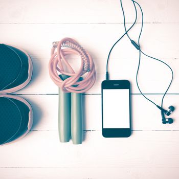 fitness equipment : running shoes,jumping rope and phone on white wood table vintage style