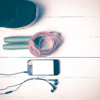 fitness equipment : running shoes,jumping rope and phone on white wood table vintage style