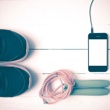 fitness equipment : running shoes,jumping rope and phone on white wood table vintage style