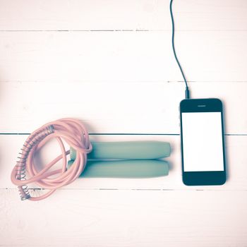 fitness equipment : jumping rope and phone on white wood table vintage style