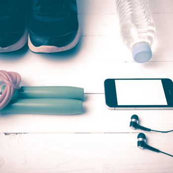 fitness equipment : running shoes,jumping rope,phone and water bottle on white wood table vintage style