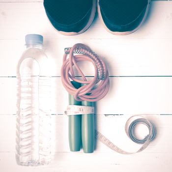 fitness equipment : running shoes,jumping rope,measuring tape and water bottle on white wood table vintage style