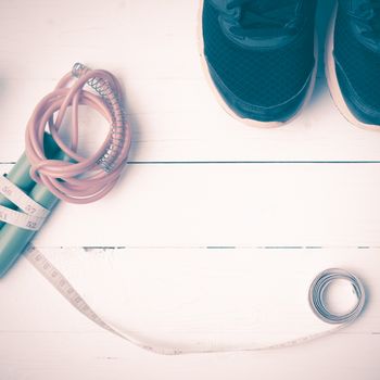 fitness equipment : running shoes,jumping rope and measuring tape  on white wood table vintage style