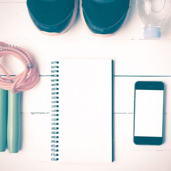 fitness equipment : running shoes,jumping rope,drinking water,notebook and phone on white wood table vintage style