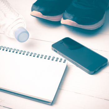 fitness equipment : running shoes,drinking water,notebook and phone on white wood table vintage style