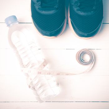 fitness equipment : running shoes,drinking water and measuring tape on white wood table vintage style