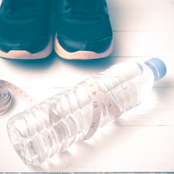 fitness equipment : running shoes,drinking water and measuring tape on white wood table vintage style
