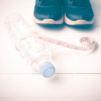 fitness equipment : running shoes,drinking water and measuring tape on white wood table vintage style