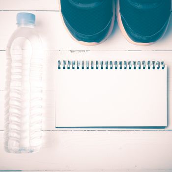 fitness equipment : running shoes,drinking water and notebook on white wood table vintage style