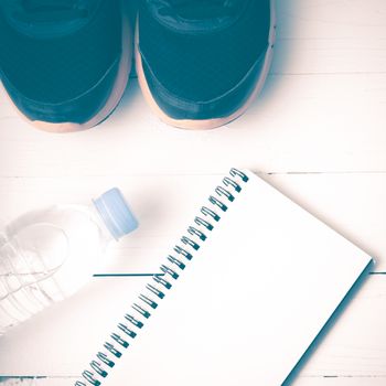 fitness equipment : running shoes,drinking water and notebook on white wood table vintage style