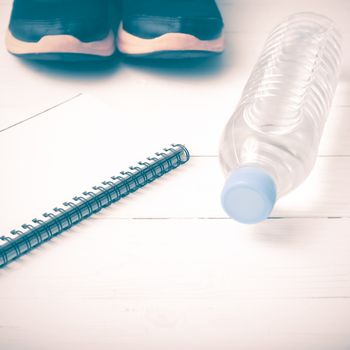 fitness equipment : running shoes,drinking water and notebook on white wood table vintage style