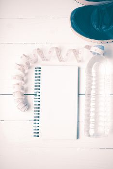 running shoes,measuring tape,drinking water and notebook on white wood table vintage style