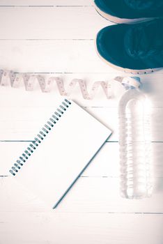 running shoes,measuring tape,drinking water and notebook on white wood table vintage style