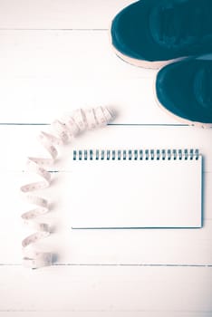 running shoes with notebook and measuring tape on white wood table vintage style