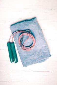 fitness equipment:blue towel,jumping rope on white wood table vintage style